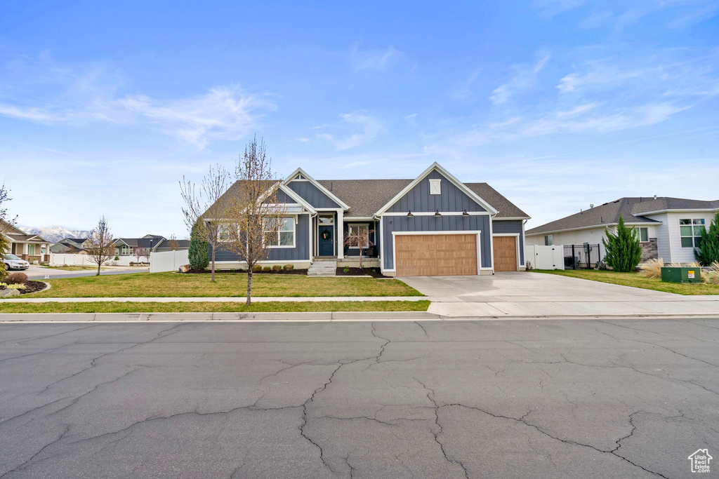 Craftsman-style home featuring fence, a garage, concrete driveway, a front yard, and board and batten siding