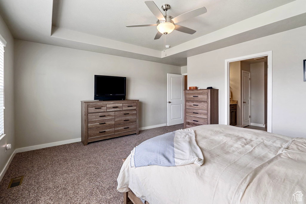 Bedroom featuring carpet flooring, visible vents, baseboards, ceiling fan, and a tray ceiling