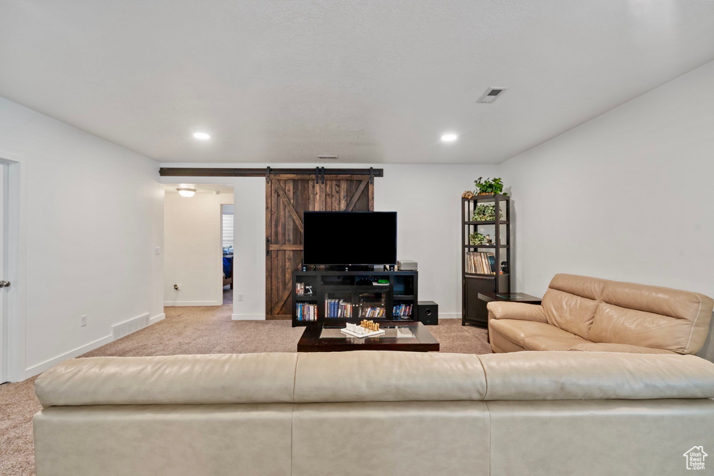 Carpeted living room with recessed lighting, baseboards, a barn door, and visible vents