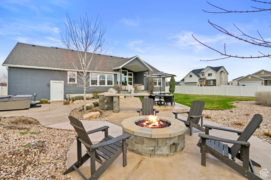 View of patio with an outdoor fire pit, fence, and a hot tub