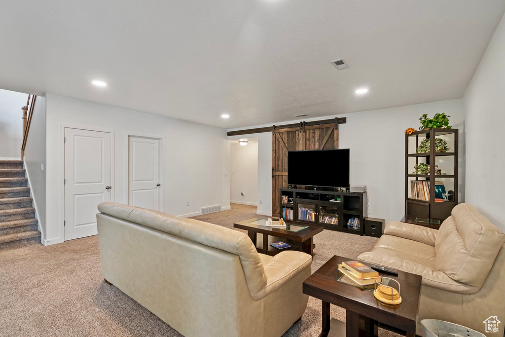 Living room featuring a barn door, visible vents, stairs, and carpet