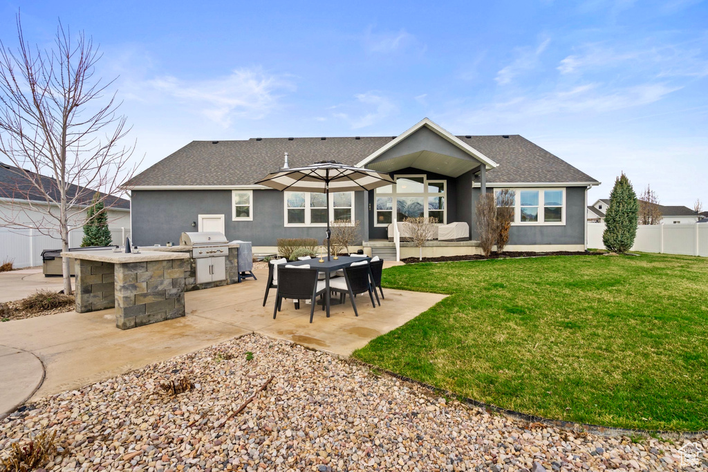 Back of property featuring roof with shingles, fence, exterior kitchen, a yard, and a patio area