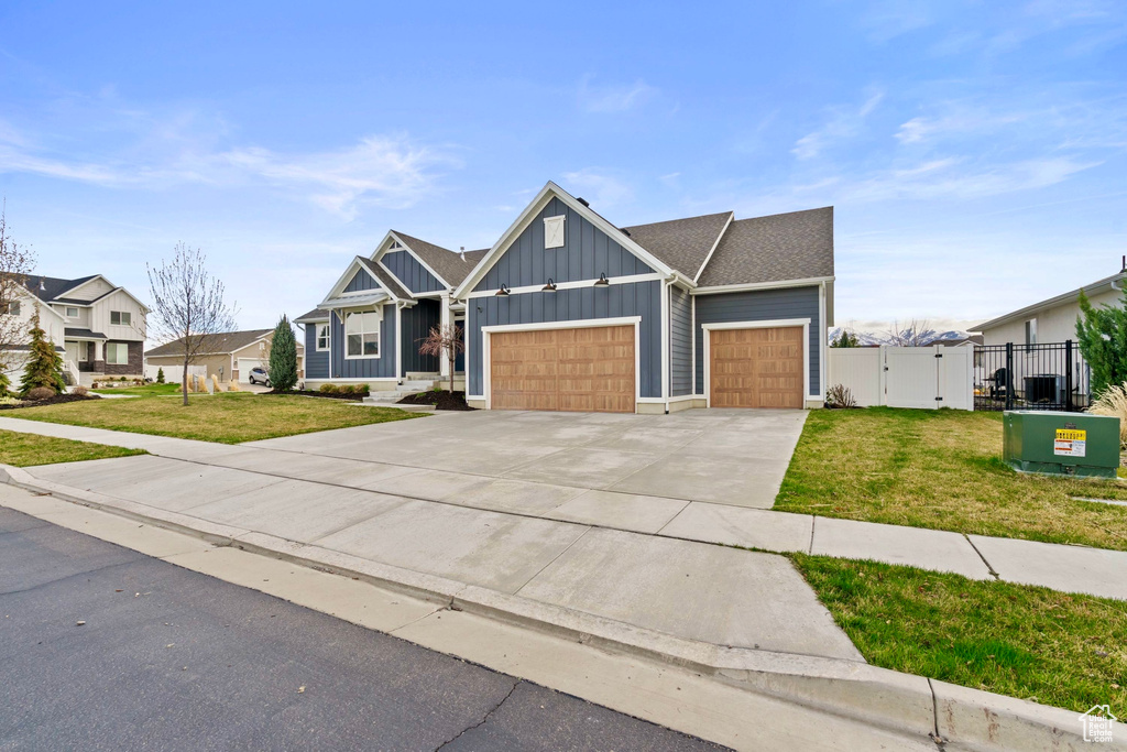View of front of property featuring a gate, a garage, concrete driveway, a front yard, and board and batten siding