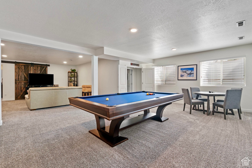 Recreation room with billiards, a barn door, light colored carpet, and visible vents