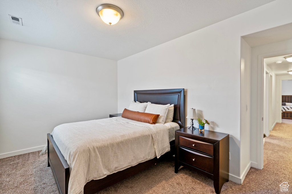 Bedroom with baseboards, visible vents, and light carpet