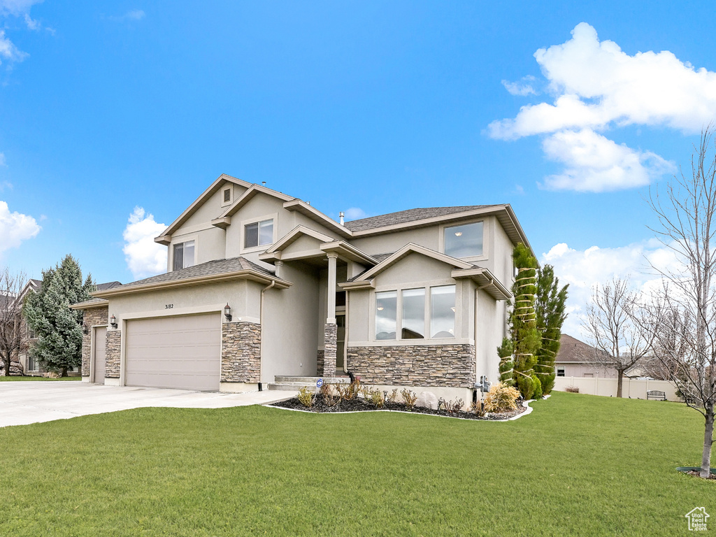 Craftsman inspired home with driveway, stucco siding, a front yard, and stone siding