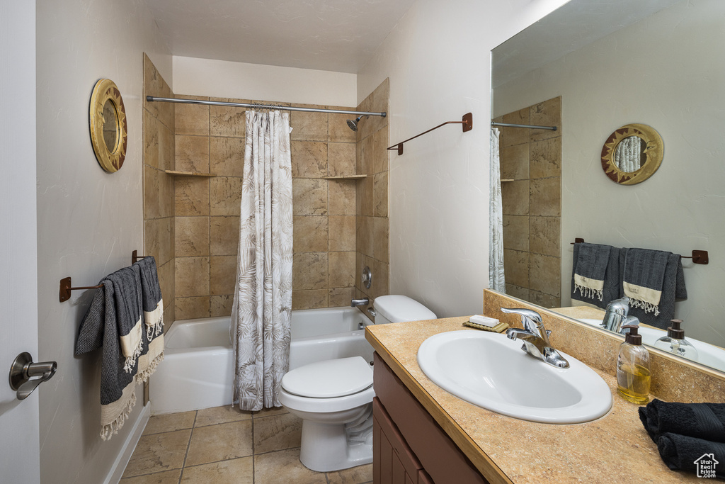 Full bathroom with toilet, shower / bathtub combination with curtain, tile patterned floors, and vanity