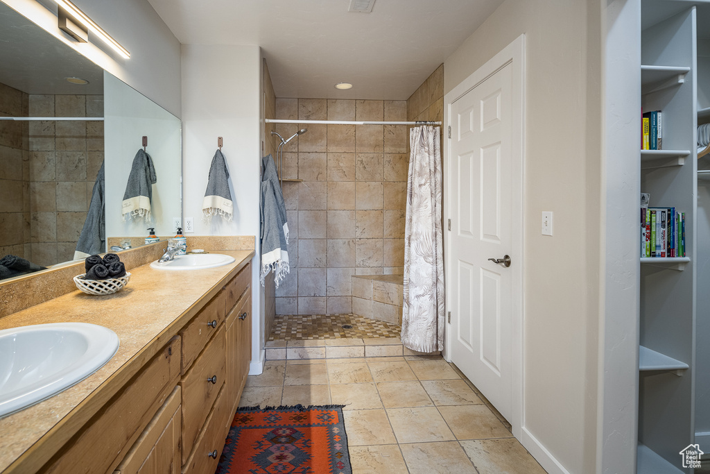 Full bathroom with double vanity, a sink, and tiled shower