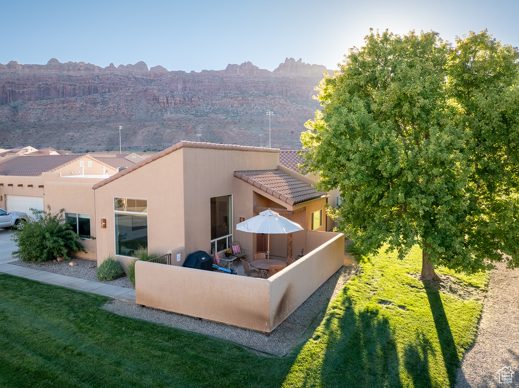 Back of property featuring a yard, stucco siding, a tiled roof, and a patio