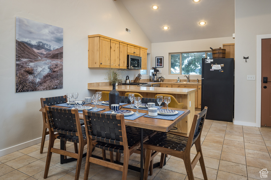 Dining area featuring light tile patterned flooring, high vaulted ceiling, and baseboards