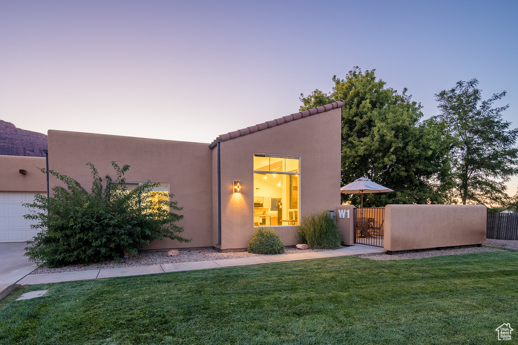 Back of property featuring a yard, a gate, stucco siding, and fence