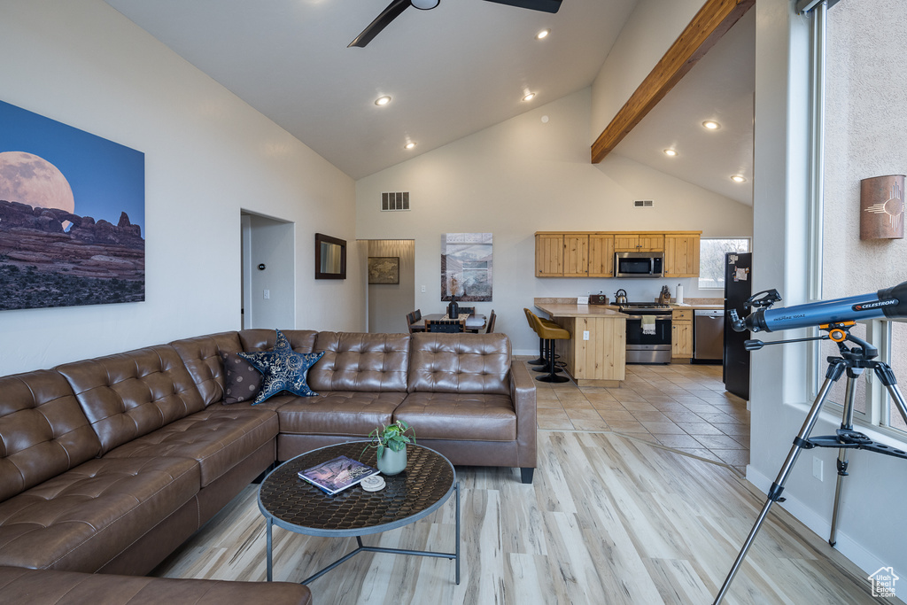 Living room with light wood finished floors, visible vents, high vaulted ceiling, and recessed lighting
