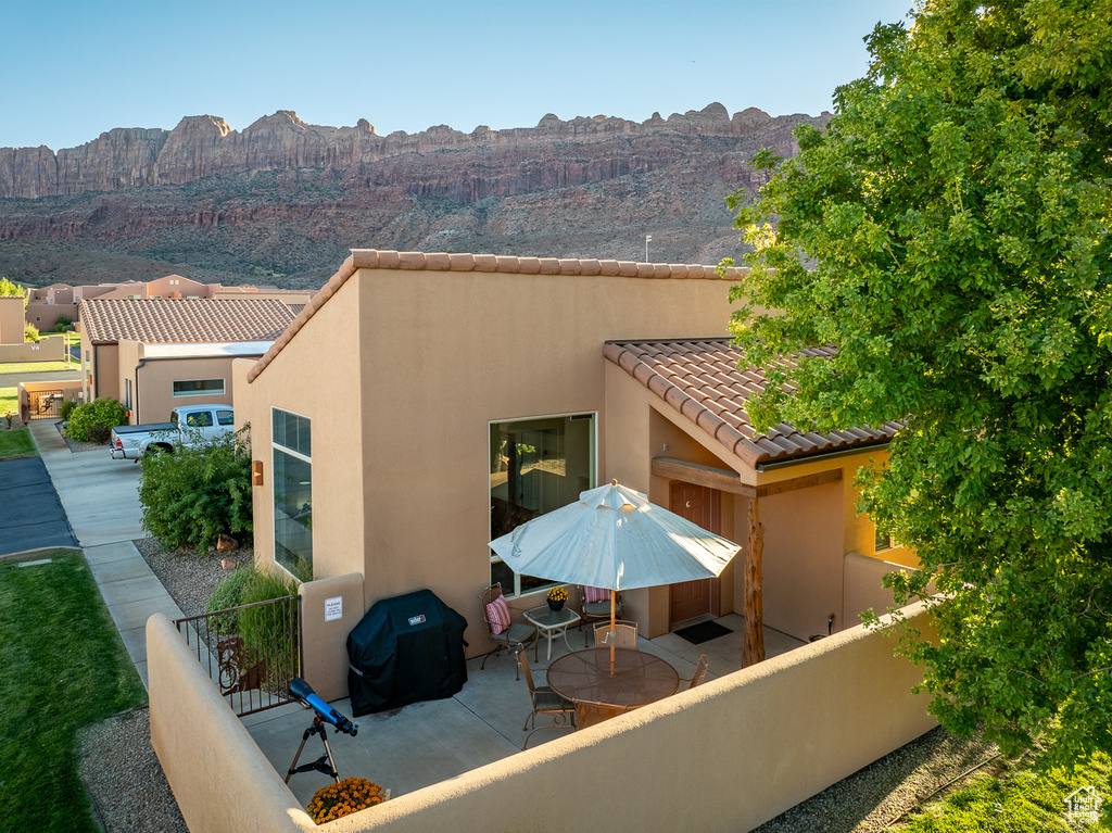 Rear view of property featuring stucco siding, fence, a tiled roof, a mountain view, and a patio area