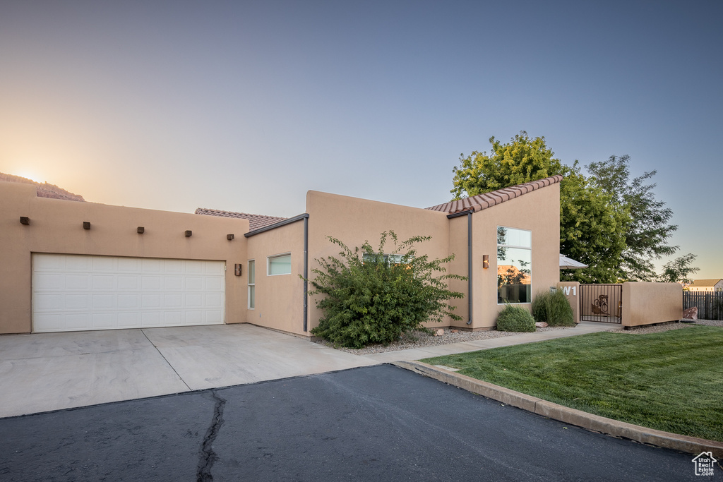 View of front of property featuring a tiled roof, concrete driveway, stucco siding, and an attached garage