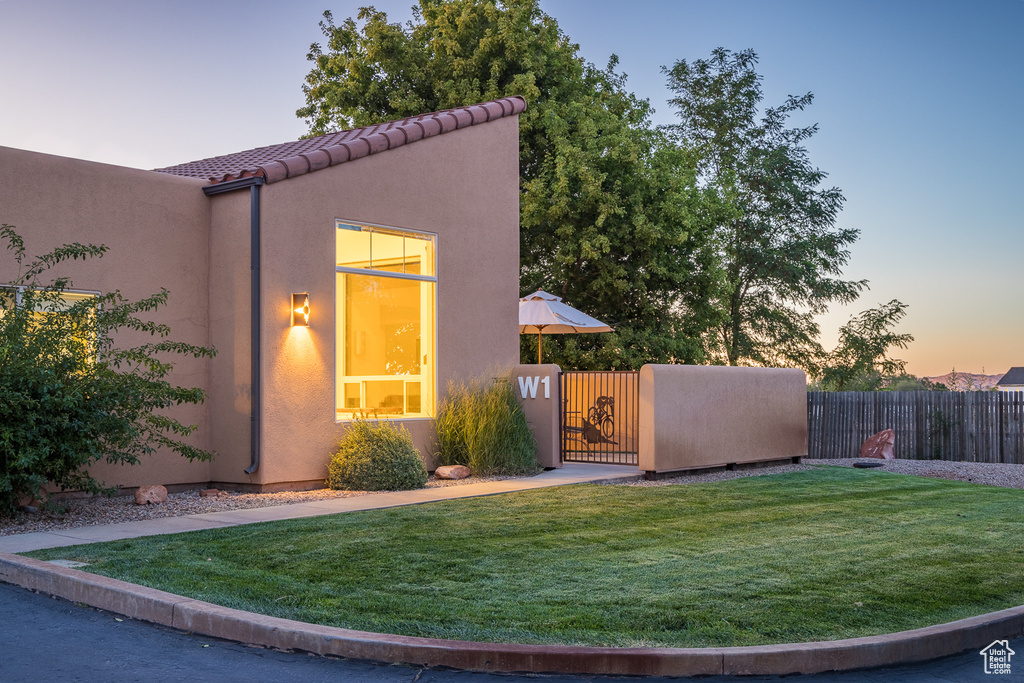View of front of house featuring stucco siding, fence, a tiled roof, a gate, and a front lawn