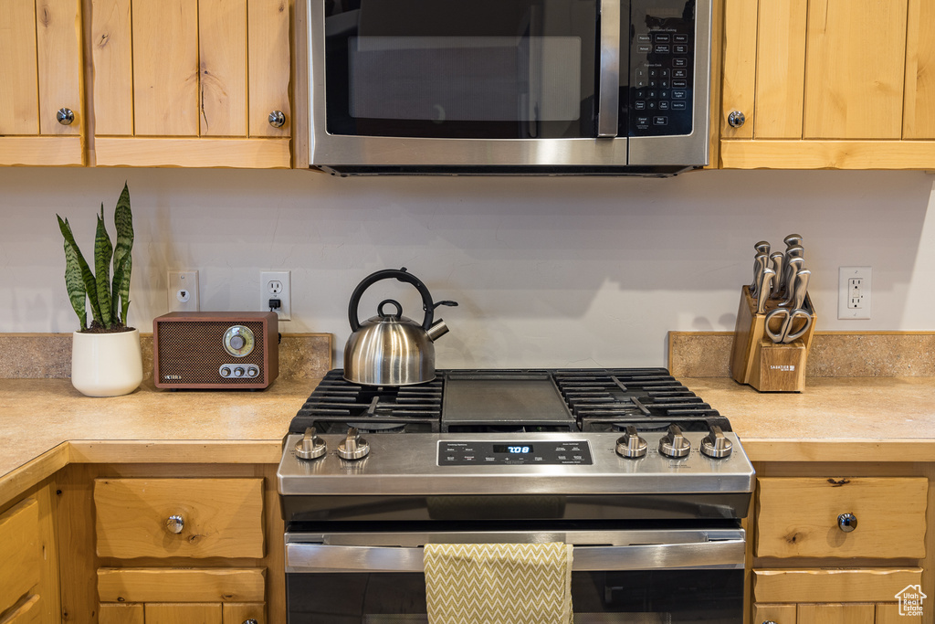 Kitchen with light countertops and appliances with stainless steel finishes