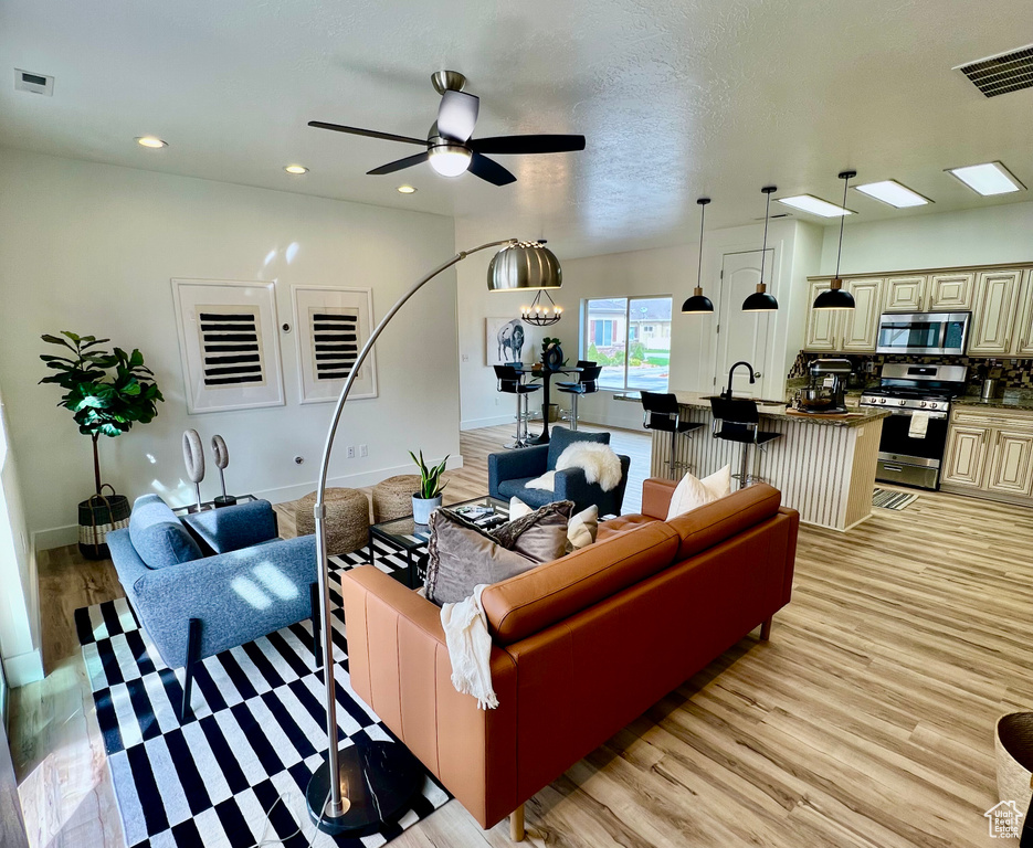 Living room featuring light wood-style floors, a ceiling fan, recessed lighting, and baseboards