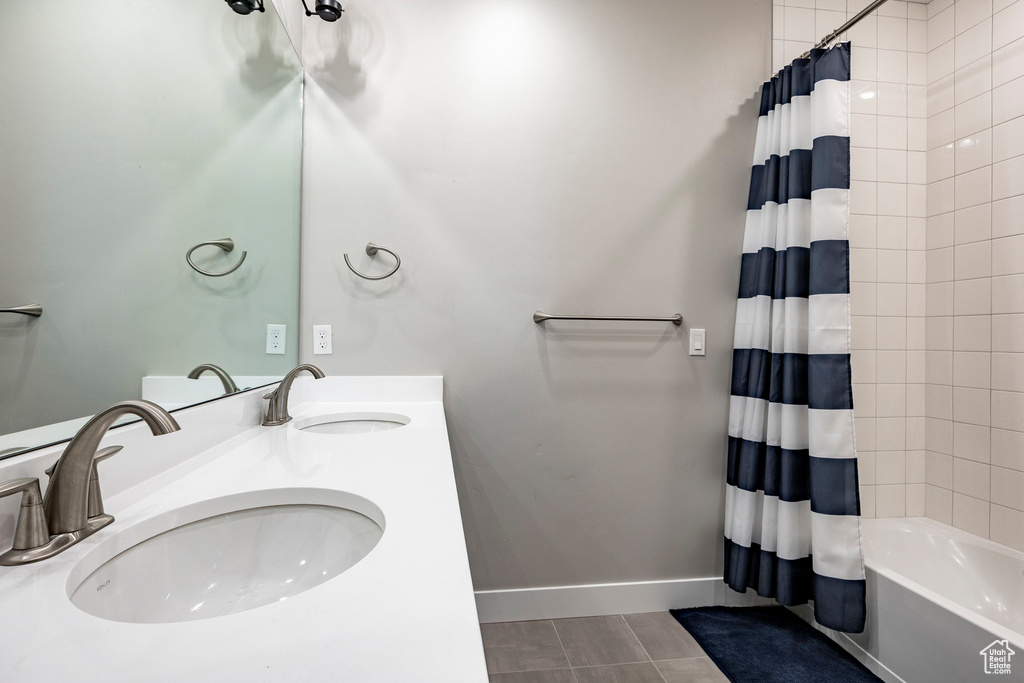 Full bathroom with a sink, baseboards, double vanity, and shower / bath combination with curtain