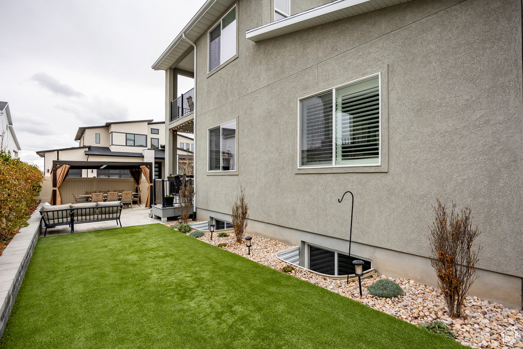Exterior space with outdoor lounge area, a lawn, stucco siding, a patio area, and a gazebo