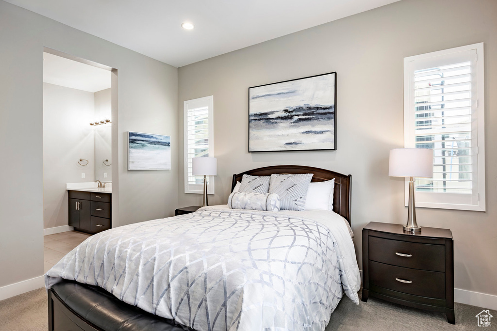 Bedroom with baseboards, multiple windows, a sink, and light carpet