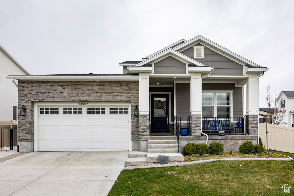 Craftsman house featuring fence, a front yard, concrete driveway, an attached garage, and a porch