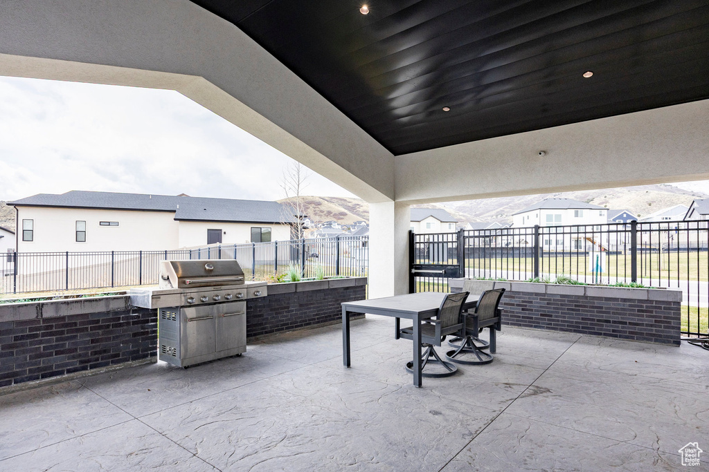 View of patio featuring outdoor dining space, fence, and a grill