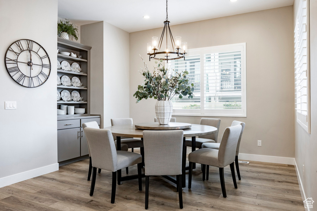 Dining space with an inviting chandelier, baseboards, light wood-style floors, and recessed lighting