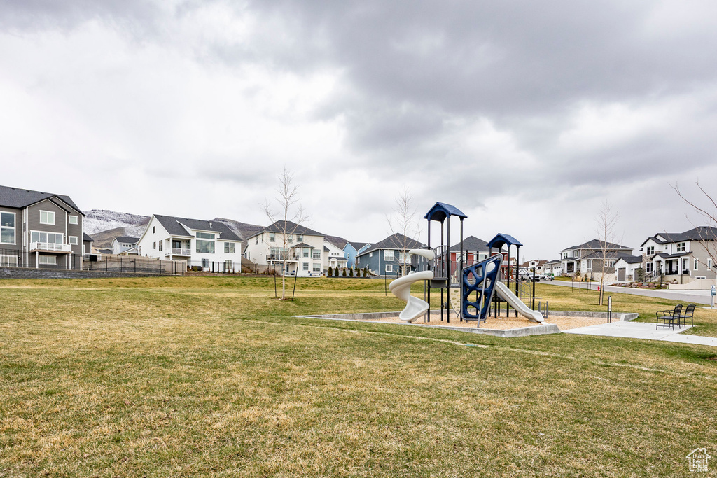 Community playground featuring a residential view, fence, and a lawn