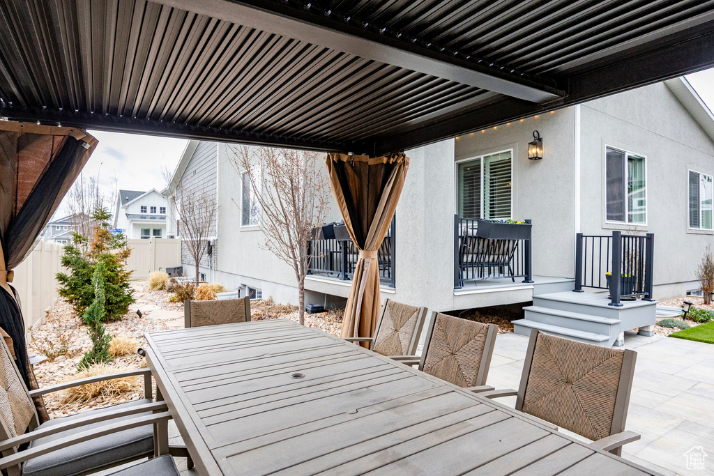 Wooden deck featuring outdoor dining area, fence, and a patio