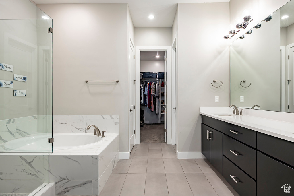 Full bathroom with vanity, a garden tub, tile patterned flooring, baseboards, and a walk in closet