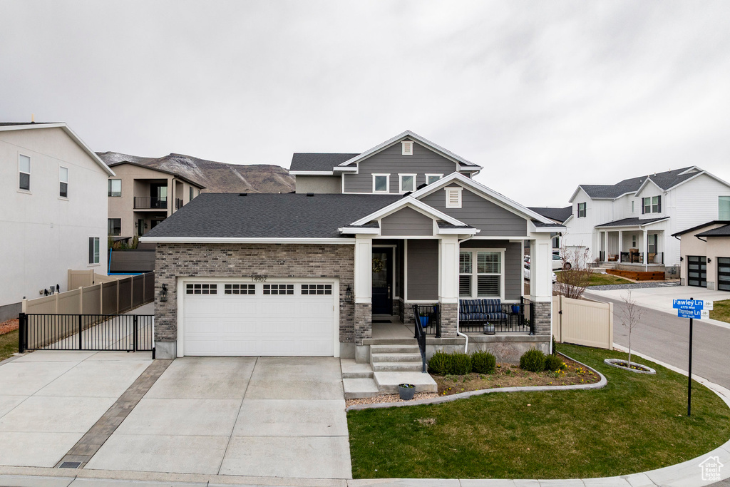 Craftsman house featuring a porch, driveway, a front yard, roof with shingles, and fence