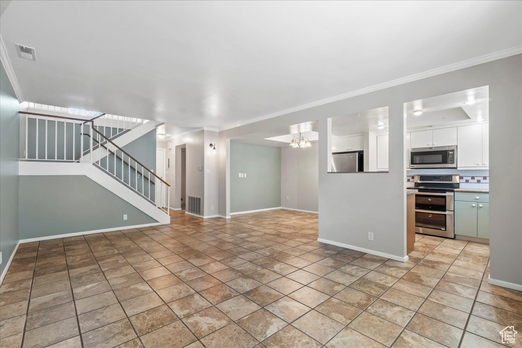 Unfurnished living room with baseboards, crown molding, stairs, a chandelier, and light stone finish floors