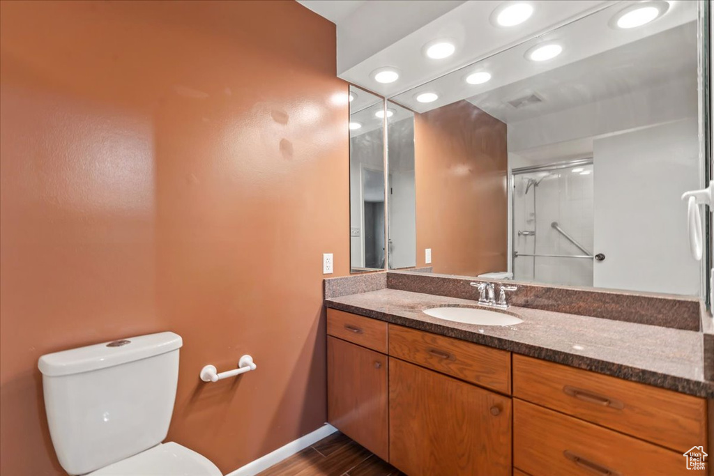Full bathroom featuring vanity, toilet, a shower with door, recessed lighting, and wood finished floors