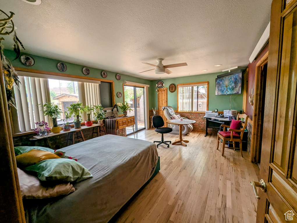 Bedroom featuring light wood-style flooring, a ceiling fan, a textured ceiling, and access to exterior