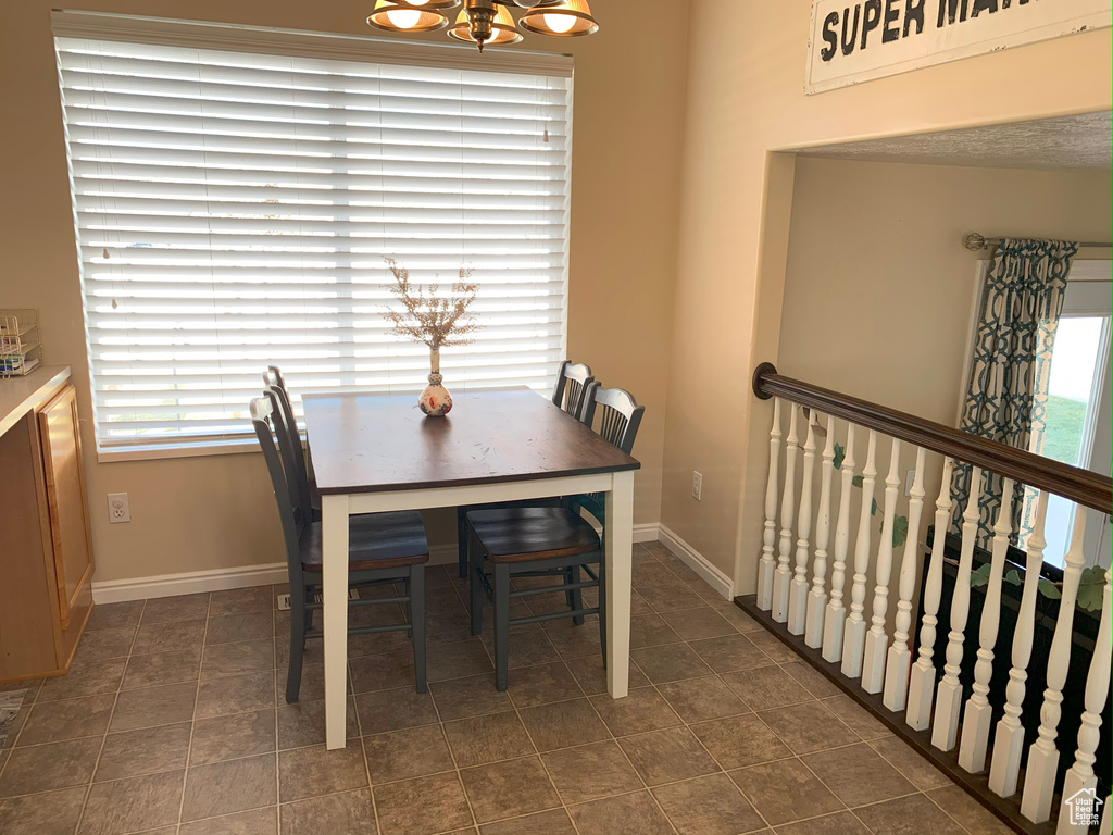 Dining room with an inviting chandelier, dark tile patterned floors, and baseboards