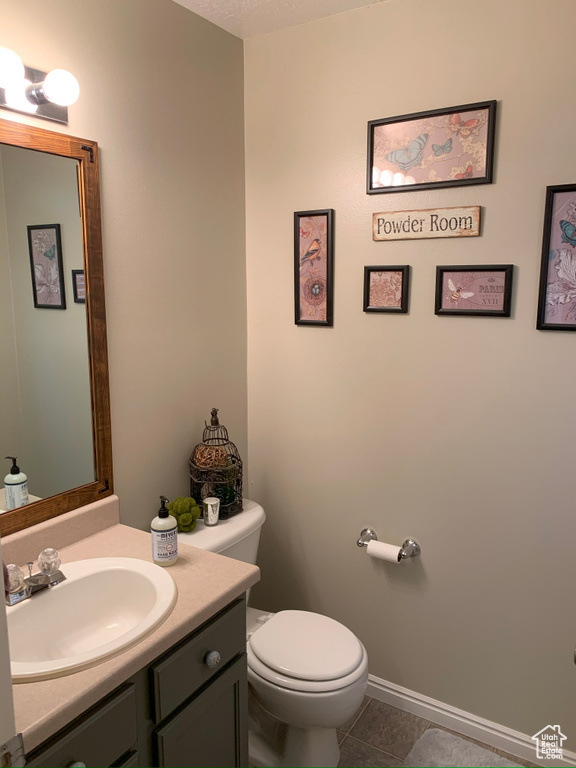Bathroom with baseboards, toilet, tile patterned flooring, and vanity