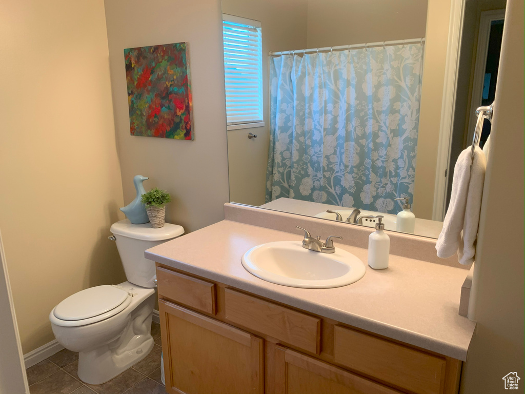 Bathroom with curtained shower, toilet, tile patterned floors, and vanity