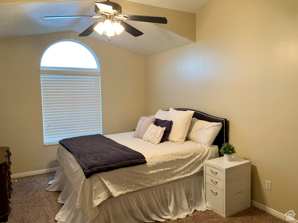 Carpeted bedroom with baseboards, lofted ceiling, and ceiling fan