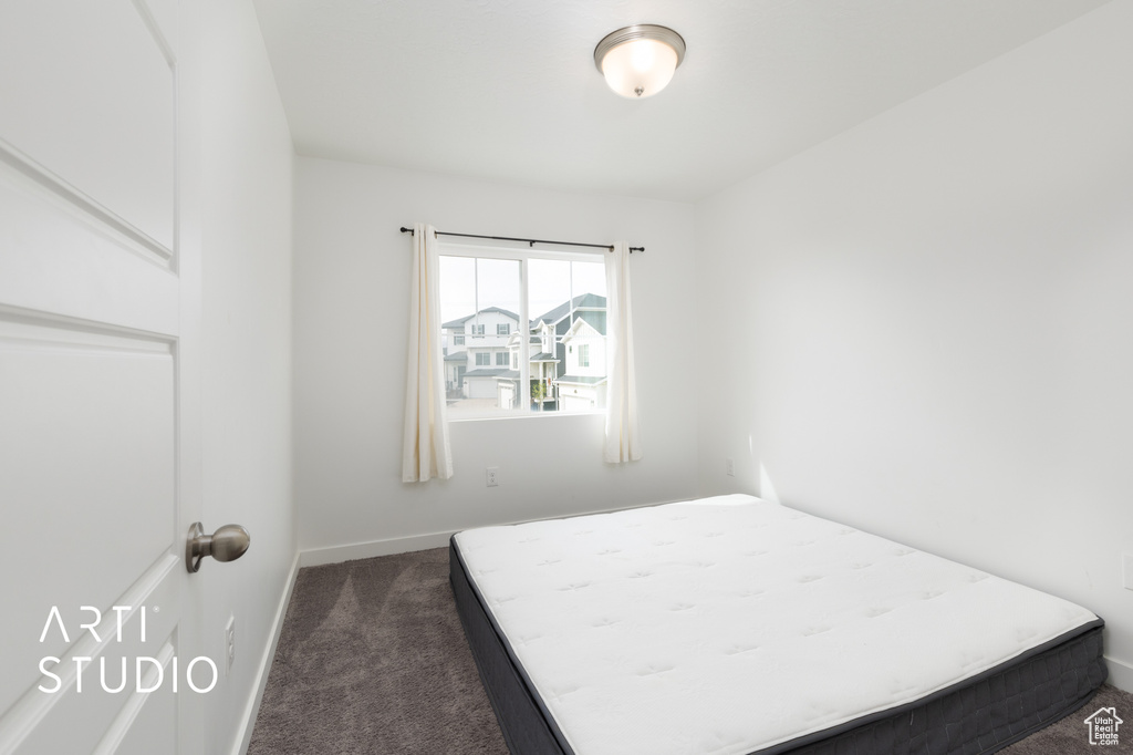 Bedroom featuring baseboards and dark carpet