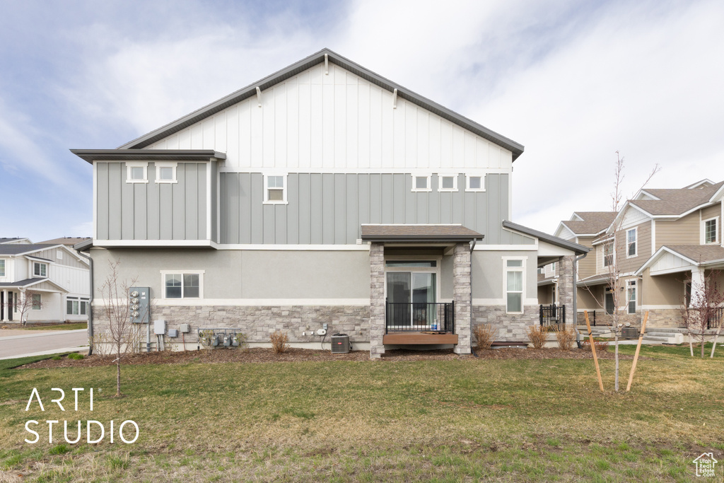 Back of house with a lawn, stone siding, board and batten siding, and a residential view