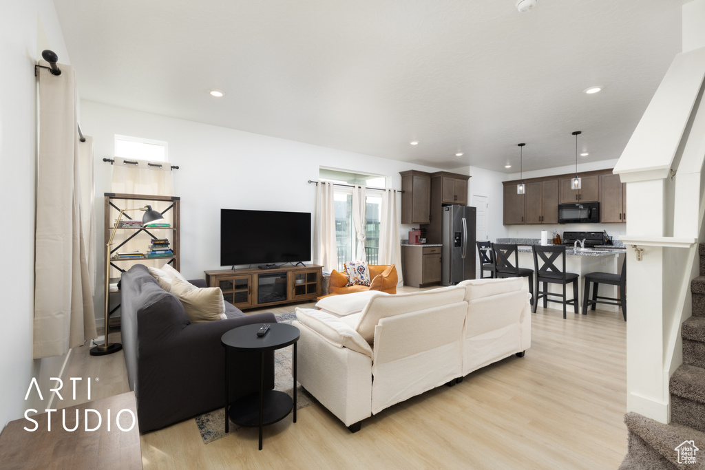 Living area with stairs, recessed lighting, and light wood-style floors