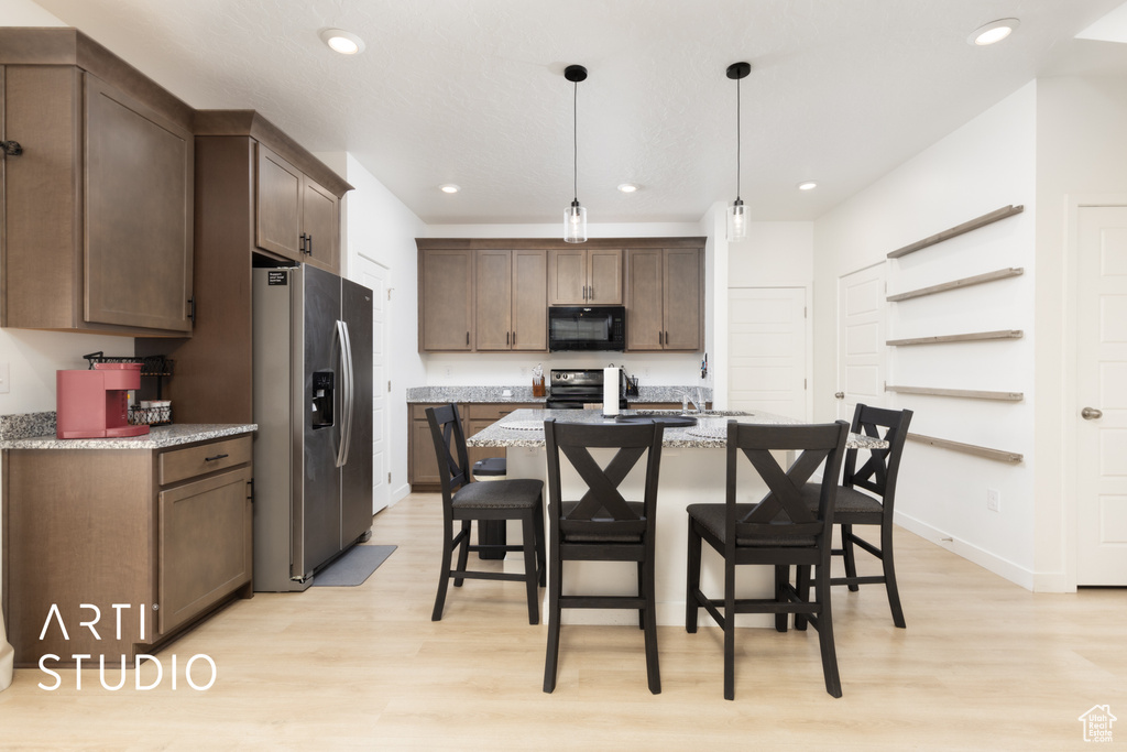 Kitchen featuring stainless steel fridge, light wood-type flooring, recessed lighting, range with electric stovetop, and black microwave