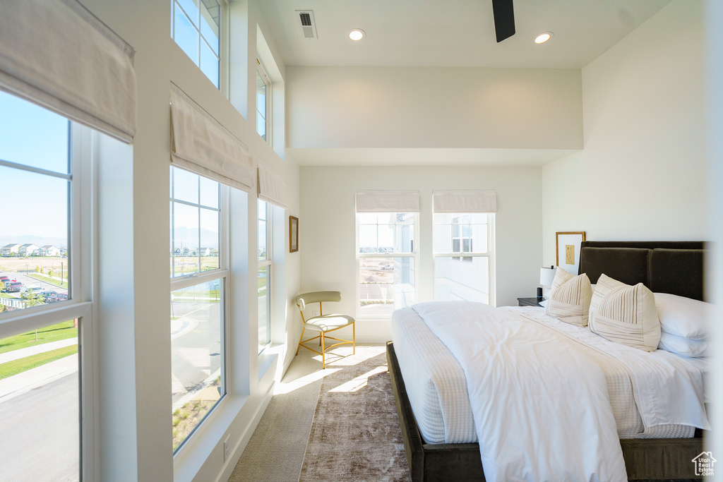 Bedroom with multiple windows, a towering ceiling, and recessed lighting