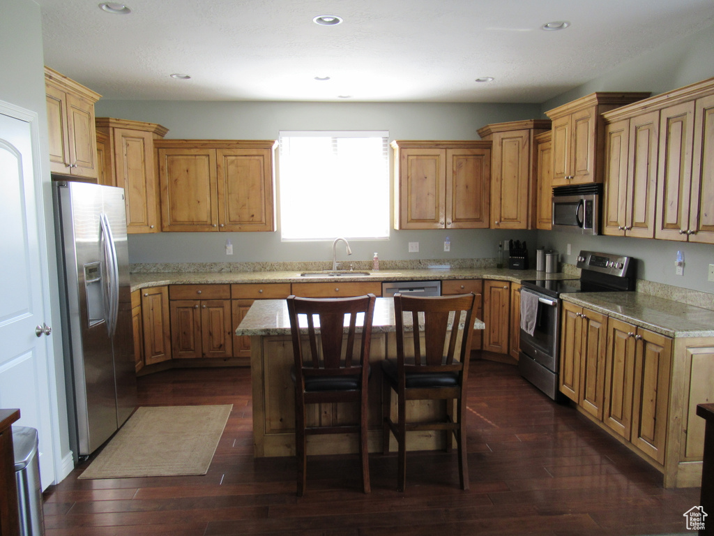 Kitchen with dark wood-style flooring, a sink, appliances with stainless steel finishes, and light stone countertops