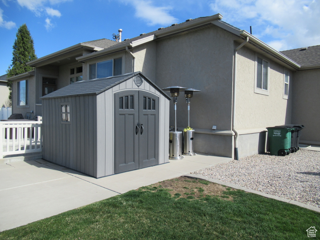 Rear view of property with an outbuilding, stucco siding, a patio area, and a storage shed