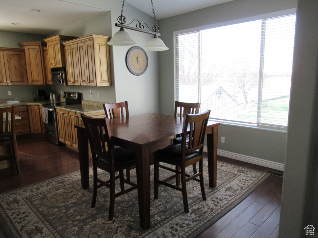 Dining space with baseboards, vaulted ceiling, and dark wood-type flooring