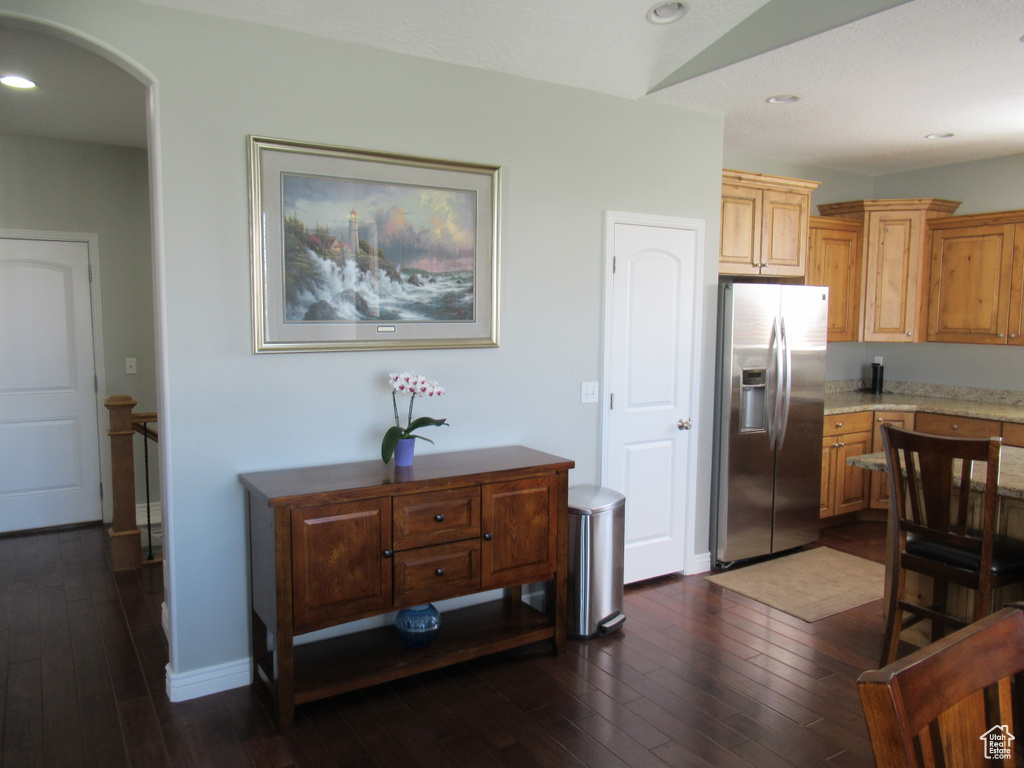 Kitchen with dark wood-style floors, recessed lighting, arched walkways, and stainless steel fridge