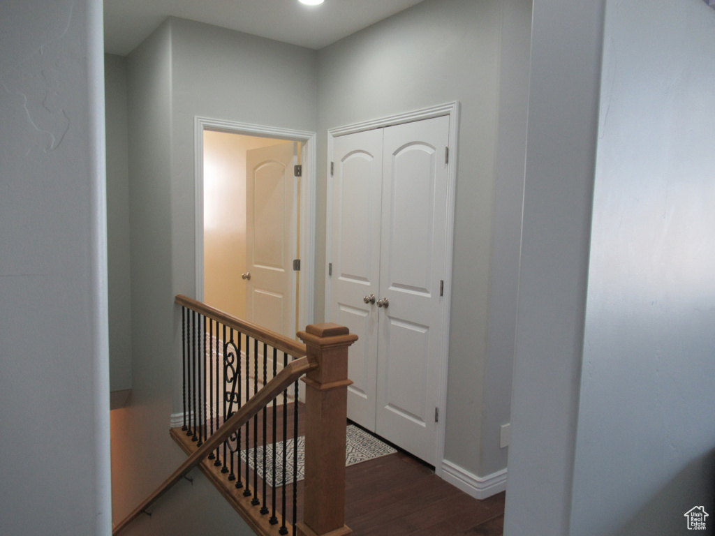 Hallway with an upstairs landing, baseboards, and wood finished floors