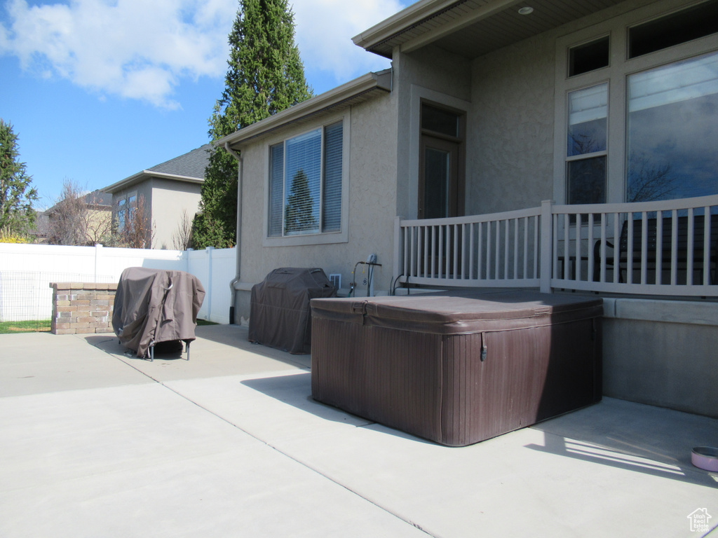 View of patio / terrace with fence, a hot tub, and a grill