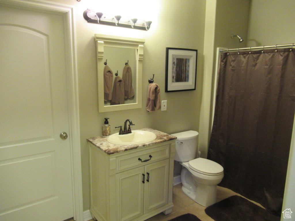 Full bathroom with toilet, vanity, tile patterned floors, and a shower with shower curtain